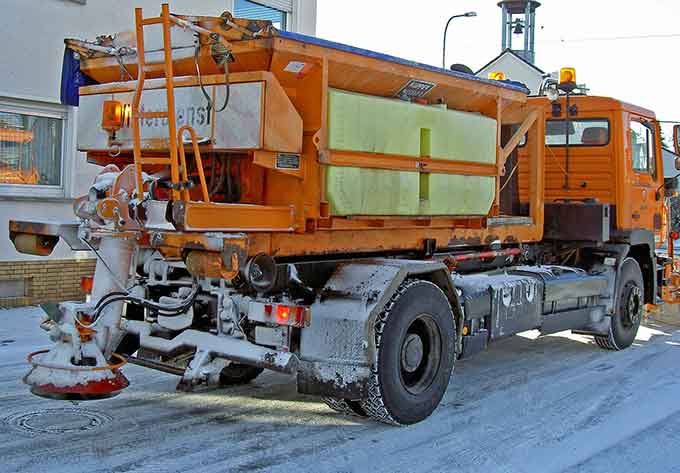 Ein Streufahrzeug streut im Winter Salz auf die Straße